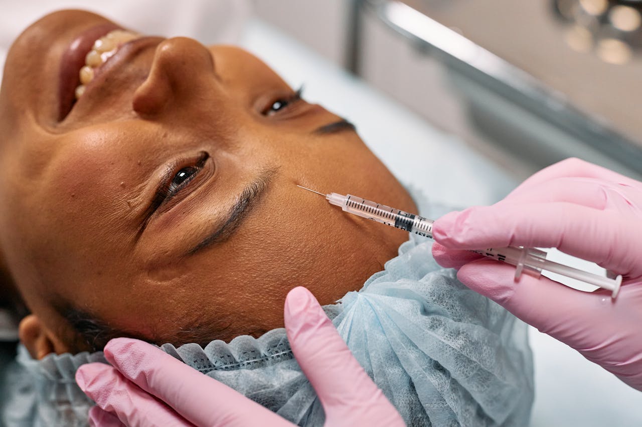 pexels-photo-7581577 Close-up of a woman receiving a cosmetic injection on her forehead in a clinical setting.
